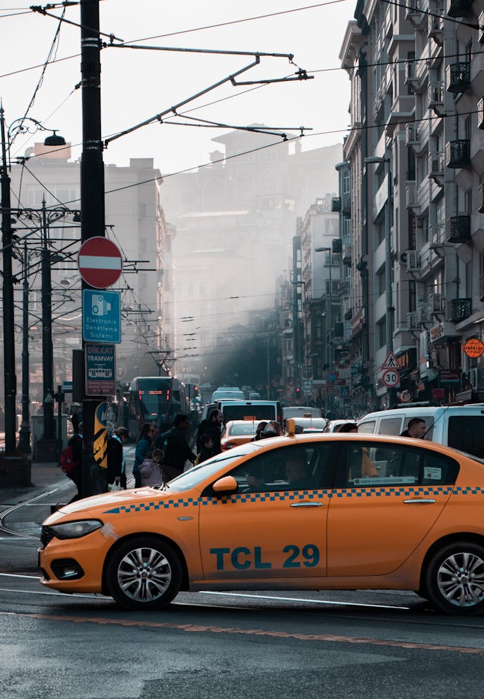 A bustling city street scene featuring a yellow taxi amidst traffic and pedestrians.