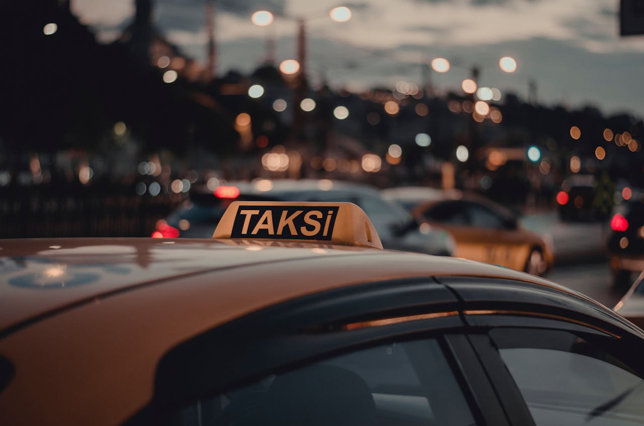 Close-up of a taxi with a 'Taksi' sign on a busy Istanbul street at night with bokeh lights.
